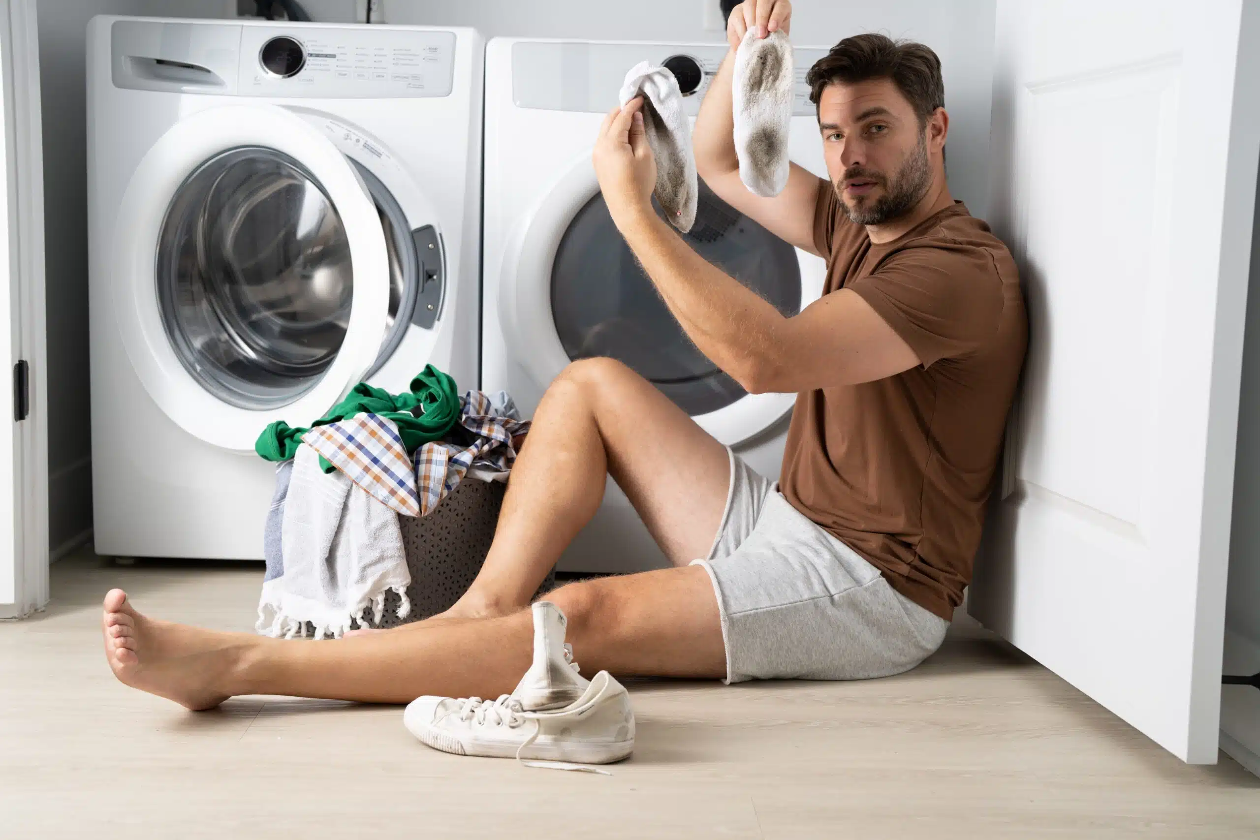 Man,Sorting,Clothes,Near,Washing,Machine.,Man,Sits,On,The